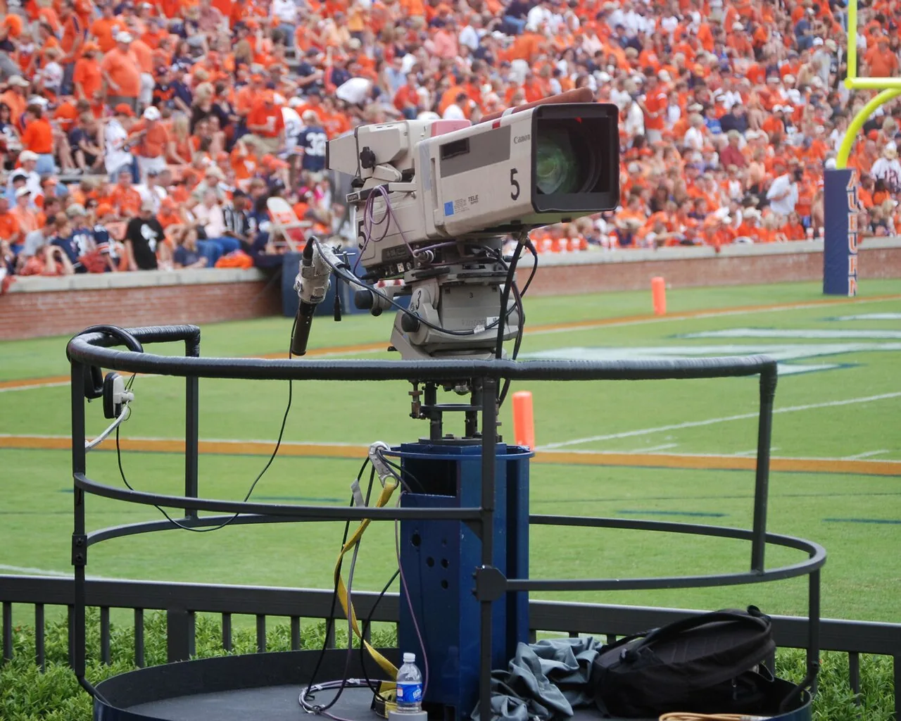 Television camera mounted on a mobile platform beside a college football field