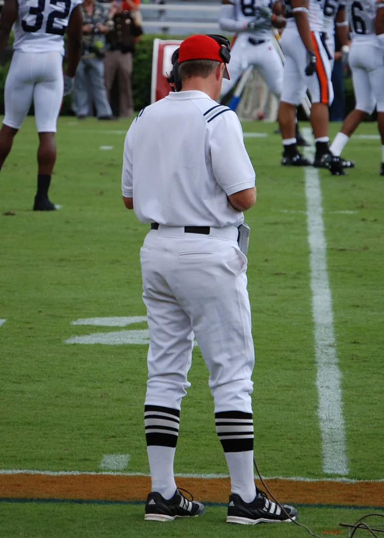 College football sideline official wearing a red cap