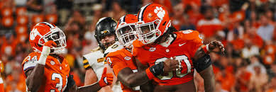 Clemson Tigers football players wearing orange jerseys celebrating together on the field after a successful play or score during live game action, demonstrating team unity and enthusiasm.