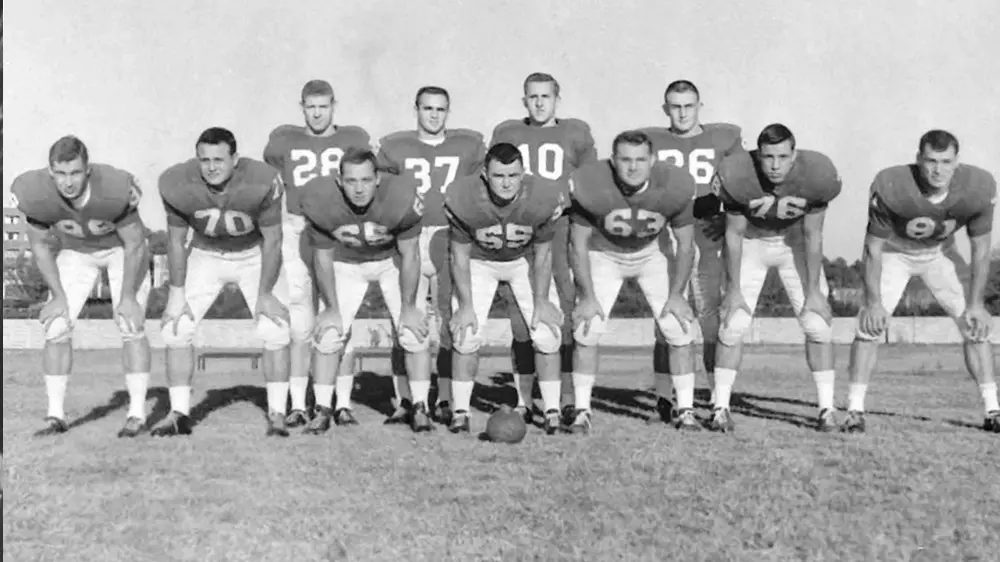Black and white photograph of a Georgia offensive line from an earlier era, players crouched in three-point stances in a row on the practice field