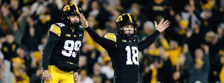 Iowa Hawkeyes players in black and gold jerseys celebrating on the field during a game
