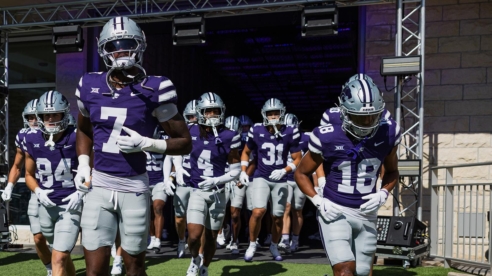 Kansas State players in purple jerseys exiting the tunnel