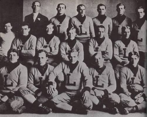Black and white team portrait of early LSU players in letterman sweaters marked with a large L, seated and standing in three rows