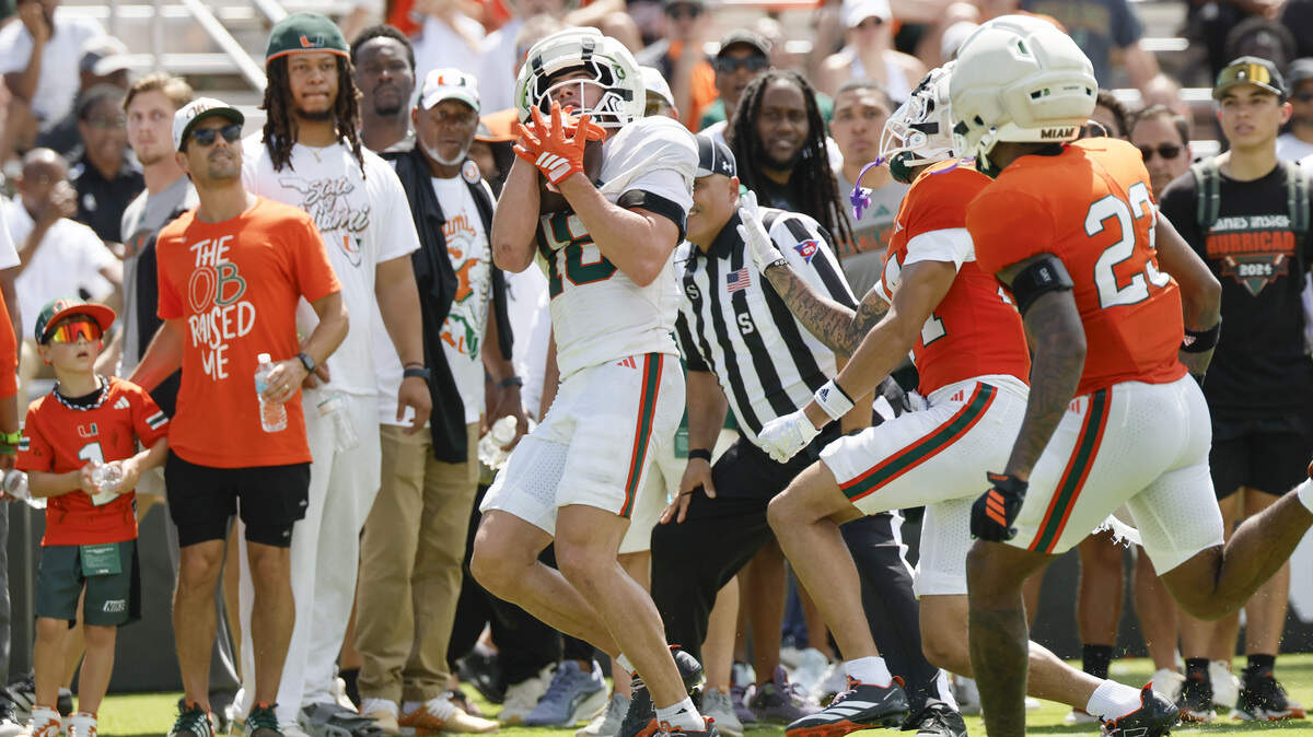 Miami Hurricanes players celebrating while wearing or presenting the iconic Turnover Chain, a glittering diamond-studded chain worn after a player forces a turnover, showcasing Miami's famous swag tradition.