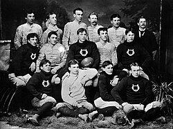 Black and white team photograph of an early Nebraska football team seated together with a football