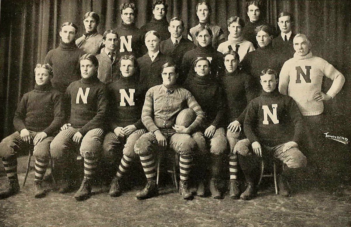 Sepia-toned portrait of an early Nebraska football squad in heavy knit sweaters bearing the letter N