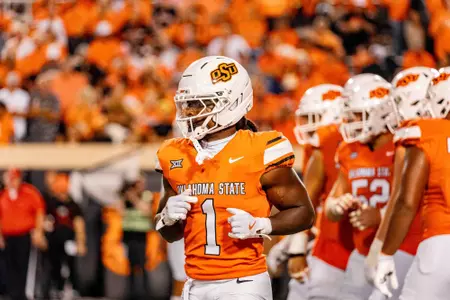 Oklahoma State Cowboys player in orange jersey running during game