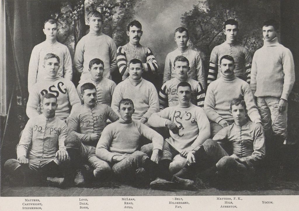 Sepia studio portrait of an 1890s Penn State football squad in heavy sweaters, several lettered PSC, with players' surnames printed beneath the image