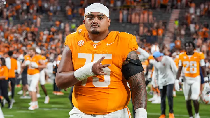 A focused Tennessee Volunteers football player wearing an orange jersey and helmet with the distinctive Power T logo, displaying intensity and determination as he prepares for the next play or action during the game.