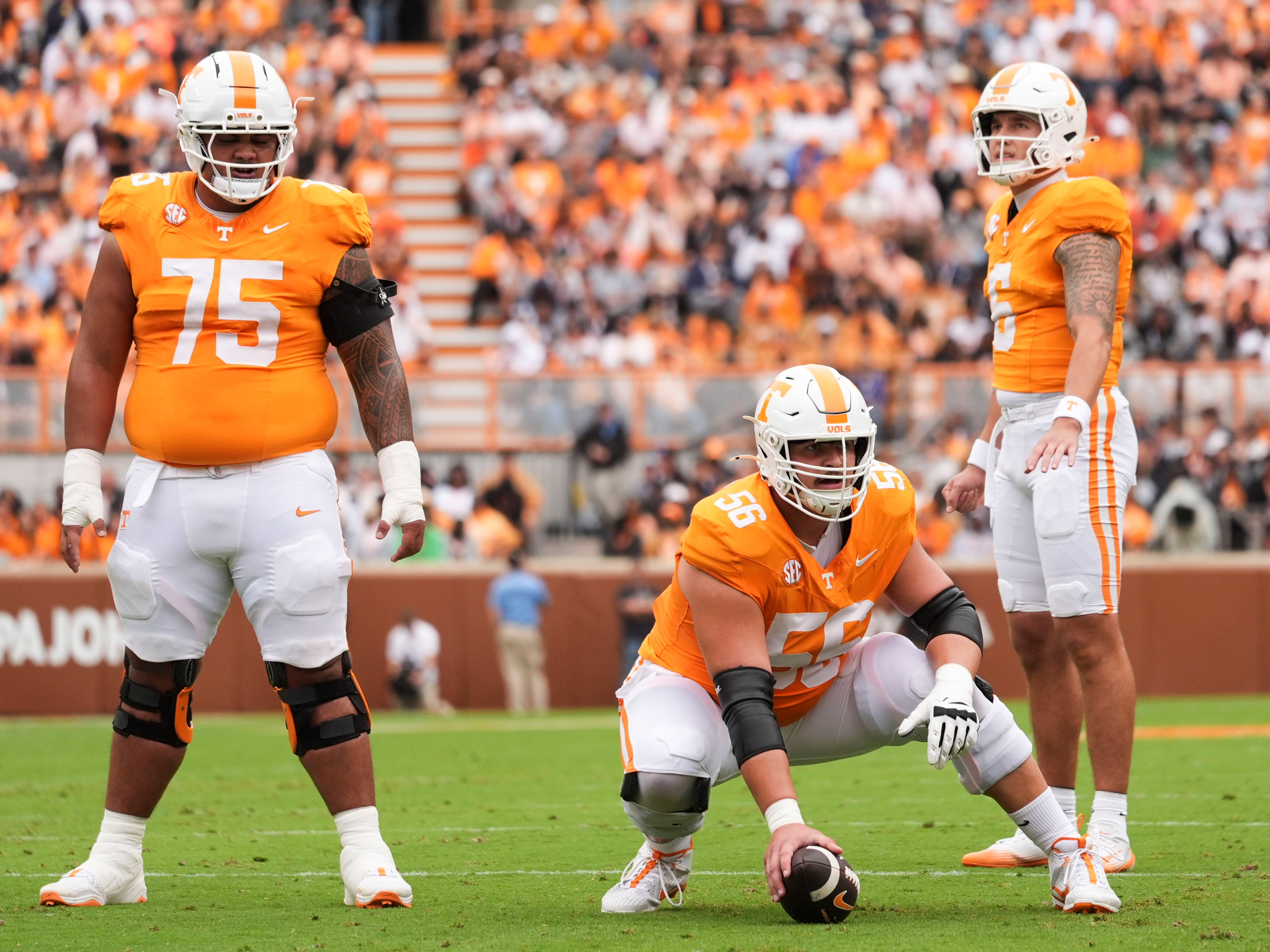 Tennessee Volunteers football players wearing orange jerseys with white numbers celebrating together on the playing field during an exciting moment in the game. The team displays unity, passion, and enthusiasm as they celebrate a successful play or score.