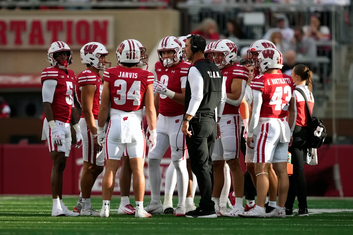 Wisconsin coach with players on the sideline during a game