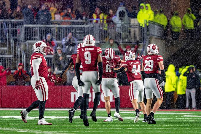 Wisconsin Badgers players in game action during wet weather conditions